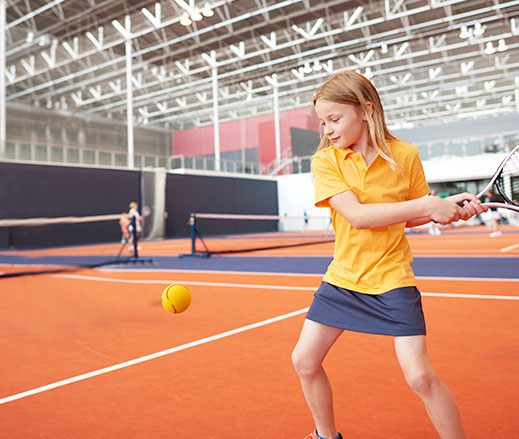 Girl playing tennis at David Lloyd Clubs.